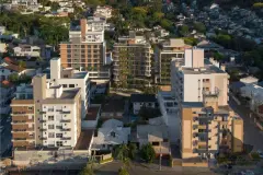 Vista aérea do empreendimento no bairro Pantanal com morros e casas ao redor — Max Studios 177 em Pantanal, Florianópolis