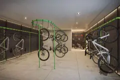 Bicicletário com racks verdes suspensos, bikes penduradas nas paredes e ferramentas de manutenção — Max Studios 177 em Pantanal, Florianópolis