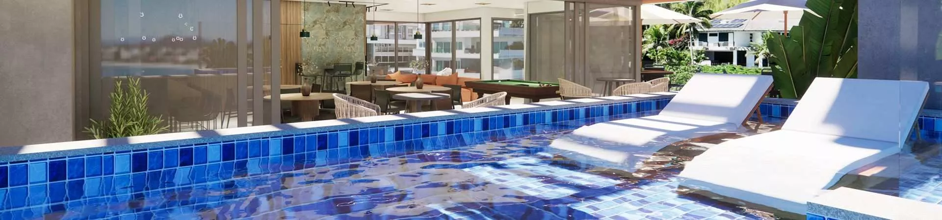 Piscina com azulejos azuis, espreguiçadeiras dentro da água e salão de jogos integrado ao fundo — Maxxi View em Jurerê, Florianópolis