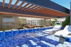 Piscina com azulejos azuis, espreguiçadeiras dentro da água e pérgola de madeira, ângulo alternativo — Maxxi View em Jurerê, Florianópolis