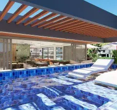 Piscina com azulejos azuis e espreguiçadeiras dentro da água, formato retrato — Maxxi View em Jurerê, Florianópolis