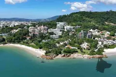 Vista aérea da localização com praia de areia, mar azul e cidade ao fundo — Maxxi View em Jurerê, Florianópolis