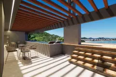 Terraço coberto por pérgola com vista para o mar e montanhas, mesas, cadeiras e espreguiçadeiras — Maxxi View em Jurerê, Florianópolis
