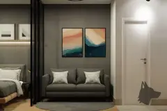 Sala do studio com sofá cinza e quadros abstratos, quarto ao fundo separado por divisória de vidro — Maxxi View em Jurerê, Florianópolis