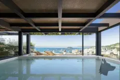 Piscina coberta com teto ripado de madeira e espreguiçadeiras com vista para o mar de Jurerê — Meraki Allure em Jurerê, Florianópolis