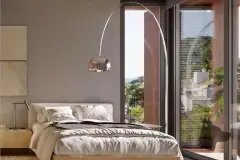 Suíte com cama de casal, abajur de arco cromado e janela com vista para morros e vegetação — Meraki Allure em Jurerê, Florianópolis