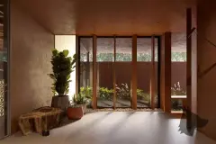 Hall de entrada com paredes de corten, vasos grandes, janelas verticais e letreiro Coworking — Meraki Allure em Jurerê, Florianópolis