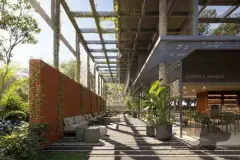 Passagem coberta com pergolado metálico, jardim vertical em parede de corten e Coffee and Market ao fundo — Meraki Allure em Jurerê, Florianópolis