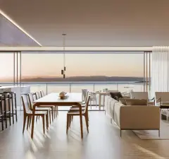 Sala de estar e jantar em retrato com mesa de jantar, sofá bege e vista para o pôr do sol sobre o mar — Meraki Sunset em João Paulo, Florianópolis