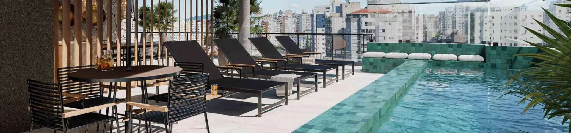Piscina rooftop linear com azulejos verdes, espreguiçadeiras pretas, mesa e palmeiras com vista para o centro de Florianópolis — Mirá Apartments em Centro, Florianópolis