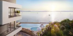 Vista aérea da piscina em curva com espreguiçadeiras e mar com barcos à vela ao entardecer — Miragio en Cacupé, Florianópolis