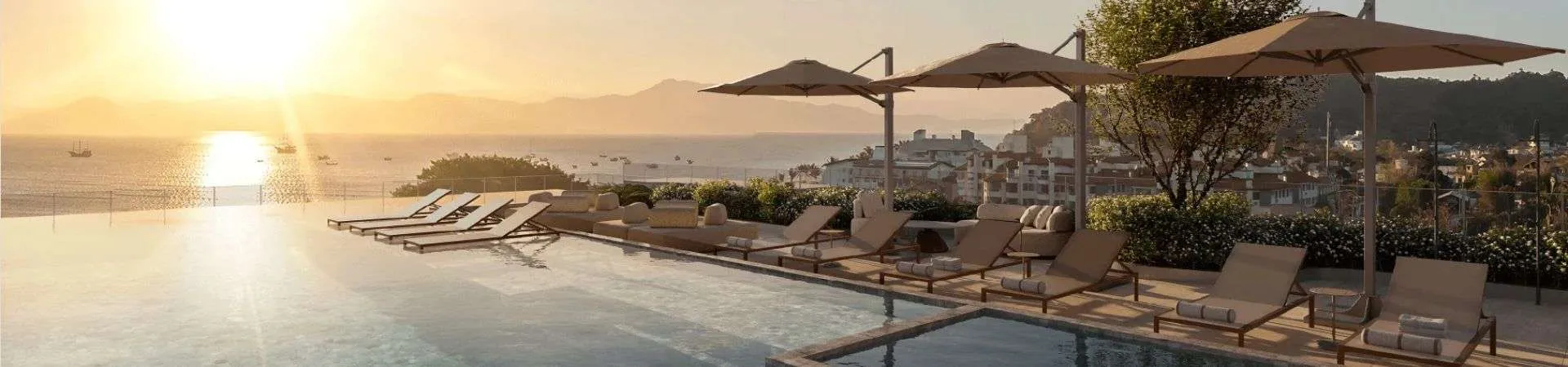 rooftop piscina infinita entardecer espreguiçadeiras guarda-sóis vista mar morros cidade — Natus em Ponta das Canas, Florianópolis
