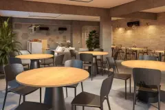 café coworking mesas redondas madeira cadeiras escuras parede tijolo pendentes iluminação quente — Neo Continente em Estreito, Florianópolis