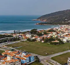 Vista aérea do bairro da Barra da Lagoa com orla, casas e morro ao fundo, ângulo alternativo — Orla da Barra em Barra da Lagoa, Florianópolis