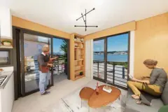 living sala render casal sofá cinza mesa café madeira estante janelas vista Baía Sul Florianópolis ponte ângulo alternativo — Park View Residence em Coqueiros, Florianópolis