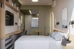studio loft integrado noturno cozinha armários verdes geladeira espelho arco iluminado cama mesa café janela vista morro — Parkside Itacorubi em Itacorubi, Florianópolis
