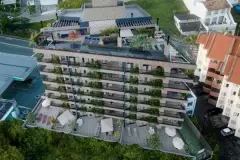 render vista aérea superior fachada edifício 8 andares revestimento pedra varandas jardins rooftop piscina bougainvillea — Playa Negra Residence em Agronômica, Florianópolis