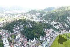 Vista aérea alternativa do morro da Cruz e região da Carvoeira com logotipo da construtora no canto — Portal da Carvoeira em Carvoeira, Florianópolis