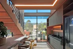 Perspectiva da sala integrada com cozinha, escada flutuante e sacada com vista para o bairro — Puerto Canas em Canasvieiras, Florianópolis