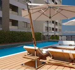 Área da piscina com deck de madeira, espreguiçadeiras e guarda-sol, ângulo lateral — Recanto dos Corais em Abraão, Florianópolis