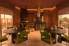 perspectiva ilustrativa salão gourmet bar mesas ovaladas pretas cadeiras veludo verde balcão ilha fogão adega vinhos parede madeira ripas LED entardecer — Regency Square Smart Stay em Centro, Florianópolis
