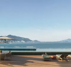perspectiva ilustrativa rooftop piscina infinita deck madeira espreguiçadeiras mesa redonda cadeiras guarda-sol vista baía montanhas formato vertical — Residencial Blue Bay em Coqueiros, Florianópolis