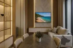 perspectiva ilustrativa sala jantar estar TV painel mármore madeira rack branco sofá bege mesa jantar pedra cadeiras flores adega vidro LED janela cortinas — Residencial Caminho do Sol em Ingleses, Florianópolis