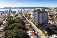 Vista aérea do empreendimento com dois edifícios altos, bairro e baía ao fundo — Rosa Branca em Canto, Florianópolis