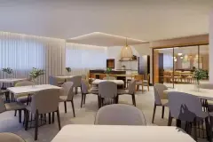 Salão de festas espaçoso com mesas redondas, cadeiras estofadas, pendentes de vime e cozinha integrada ao fundo — Rosa Branca em Canto, Florianópolis