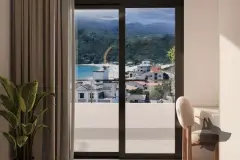 Janela de quarto com vista para praia e morro verde, planta tropical e poltrona branca à direita — Saint Humbert II em Ingleses, Florianópolis