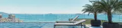 Piscina de borda infinita com espreguiçadeiras e vista panorâmica para o mar, palmeiras e guarda-corpo de vidro — Saint Zambelli em Ingleses, Florianópolis