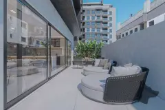 Terraço com camas redondas de vime, porta de correr de vidro para área de lazer e vista urbana — Saint Zambelli em Ingleses, Florianópolis