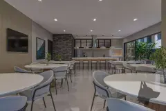 Salão de festas em ângulo diferente com mesas, cadeiras e cozinha equipada — Saint Zambelli em Ingleses, Florianópolis