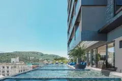 Piscina com revestimento em pastilhas azuis, vista para montanhas e mar, palmeiras e fachada do edifício — Saint Zambelli em Ingleses, Florianópolis