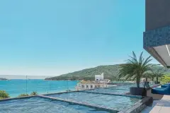 Detalhe da piscina com espreguiçadeiras, palmeira e vista para a orla e montanhas — Saint Zambelli em Ingleses, Florianópolis