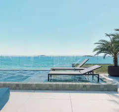 Deck da piscina de borda infinita com espreguiçadeiras, água azul e palmeira — Saint Zambelli em Ingleses, Florianópolis