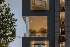 Detalhe da fachada noturna com varandas iluminadas e jardim vertical no topo do edifício — Santa 4 em Santa Mônica, Florianópolis