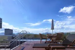 Piscina no rooftop com deck de madeira, cadeiras rattan e guarda-sol, vista panorâmica para o céu azul — Solis em Ingleses, Florianópolis