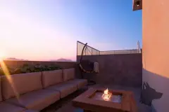 Terraço privativo ao entardecer com sofá externo, lareira de mesa e poltrona suspensa — Solis em Ingleses, Florianópolis