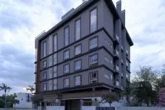 Fachada do edifício com acabamento cinza, janelas amplas e palmeiras ao redor — Solis em Ingleses, Florianópolis