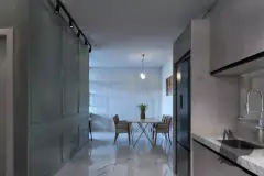 Corredor com mesa de jantar ao fundo, geladeira, spots de trilho e bancada de mármore — Solis em Ingleses, Florianópolis