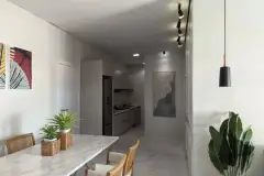 Sala de jantar com mesa de mármore e cadeiras de rattan, cozinha compacta ao fundo — Solis em Ingleses, Florianópolis