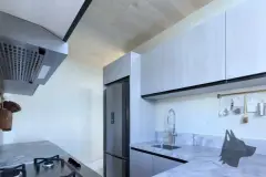 Cozinha com armários brancos, bancada de mármore, geladeira inox e coifa sobre cooktop — Solis em Ingleses, Florianópolis