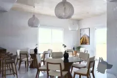 Salão de festas com mesas redondas de vidro, cadeiras brancas e luminárias pendentes globo — Solis em Ingleses, Florianópolis