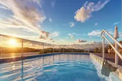 Piscina no rooftop ao pôr do sol com guarda-corpo de vidro e espreguiçadeiras ao fundo — Solis em Ingleses, Florianópolis