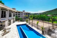 Piscina do condomínio com espreguiçadeiras, quadra de areia ao fundo e morros — Summer Park Residence - Fase 2 em Vargem do Bom Jesus, Florianópolis