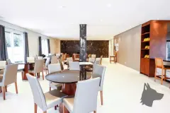 Salão de festas com mesas redondas e retangulares, cadeiras e coluna de mármore escuro — Summer Park Residence - Fase 2 em Vargem do Bom Jesus, Florianópolis