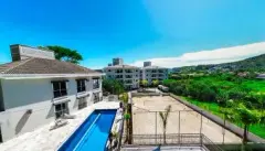 Vista lateral do edifício com piscina e quadra de areia em primeiro plano — Summer Park Residence - Fase 2 em Vargem do Bom Jesus, Florianópolis