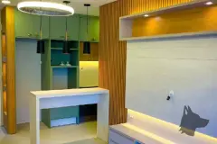 Sala integrada à cozinha com armários verdes, bancada ilha e painel ripado de madeira — Summer Park Residence - Fase 2 em Vargem do Bom Jesus, Florianópolis