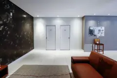 Hall de entrada do salão com parede de mármore escuro, portas brancas e sofá de couro — Summer Park Residence - Fase 2 em Vargem do Bom Jesus, Florianópolis